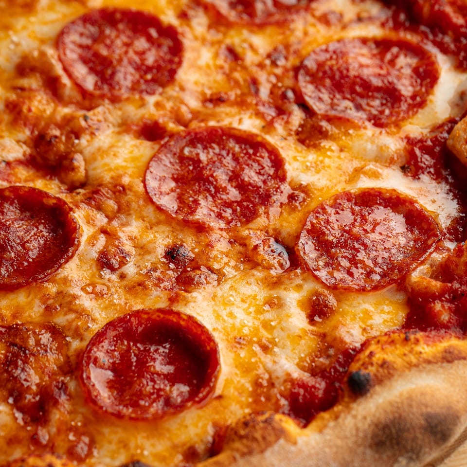 Close-up of a Smokin Chicken & Pizza pepperoni pizza with melted cheese and a crispy crust.